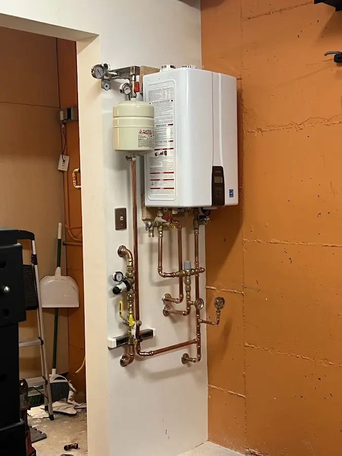 Plumbing technician inspecting water heater connections in Moyock